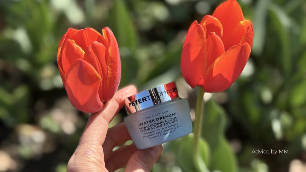 Peter Thomas Roth Water Drench Hyaluronic Cloud Hydrating Eye Gel fotografiat între două lalele roșii. Formula conține dimethicone și polysilicone-11 pentru efect de netezire și confort la aplicare.